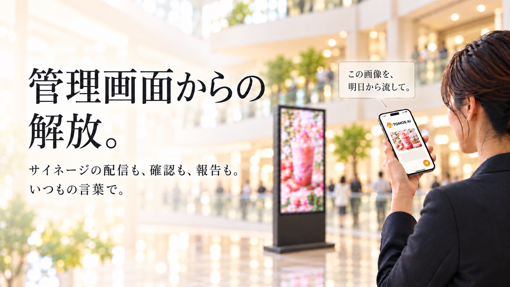 明るい商業施設。右端の担当者がTOMOS AIのスマートフォン画面から、画像を添えて配信を依頼している。細枠の明朝体の吹き出しに『この画像を、明日から流して。』と表示。